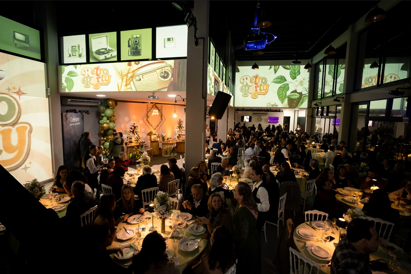 Salão da Amazzing lotado em festa com projeção temática retrô
